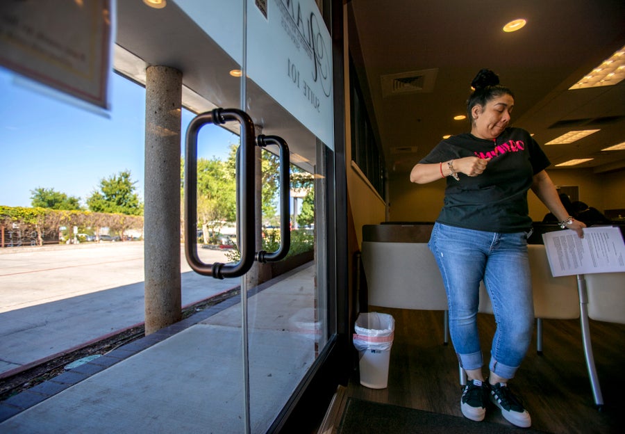 An emotional staff member waits inside the clinic doorway.